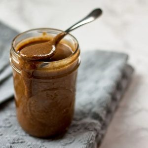 cinnamon almond nut butter jar with spoon and table cloth