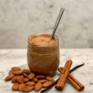 jar of vanilla almond nut butter with vanilla spice around it
